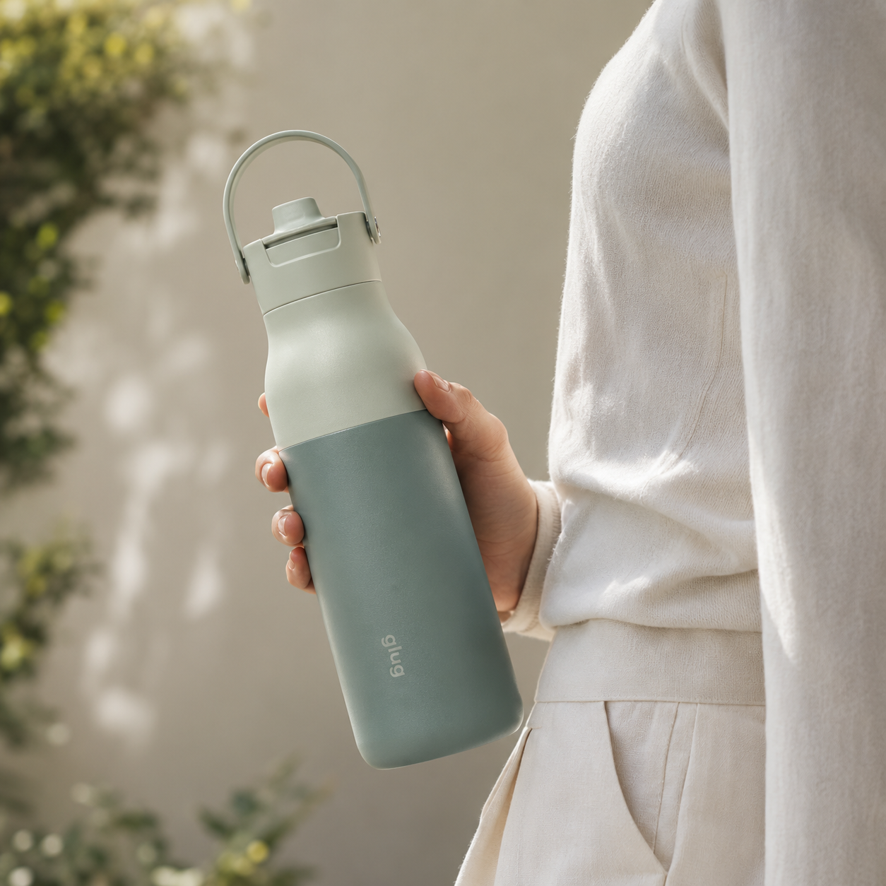 Person holding a glug Sage bottle in a natural outdoor setting